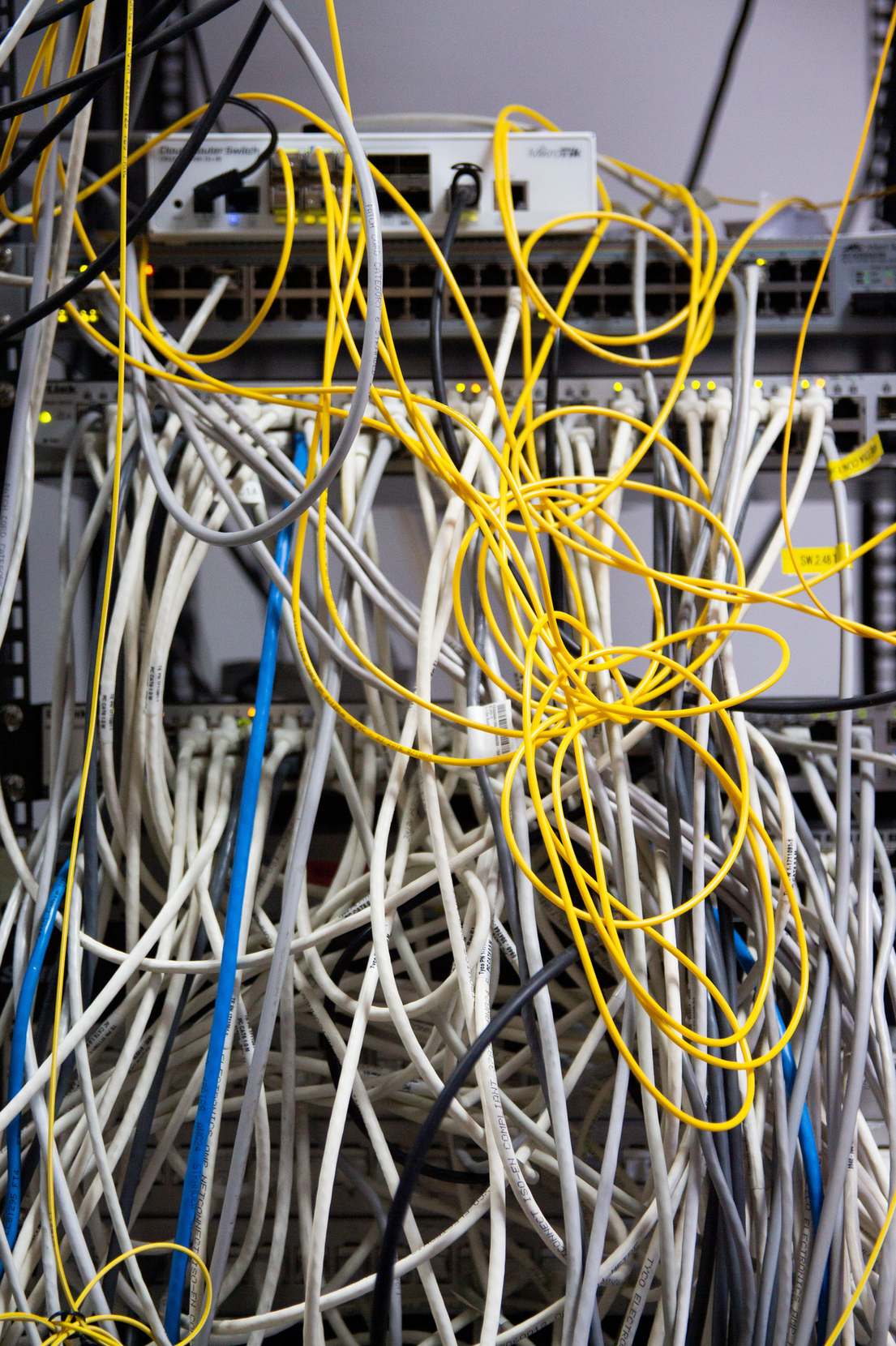 Close view of network hardware and cabling in a rack with tangled network cables in a server room